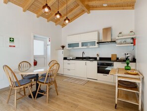 Et moderne køkken med hvide skabe, en komfur og et spiseområde med træstole.