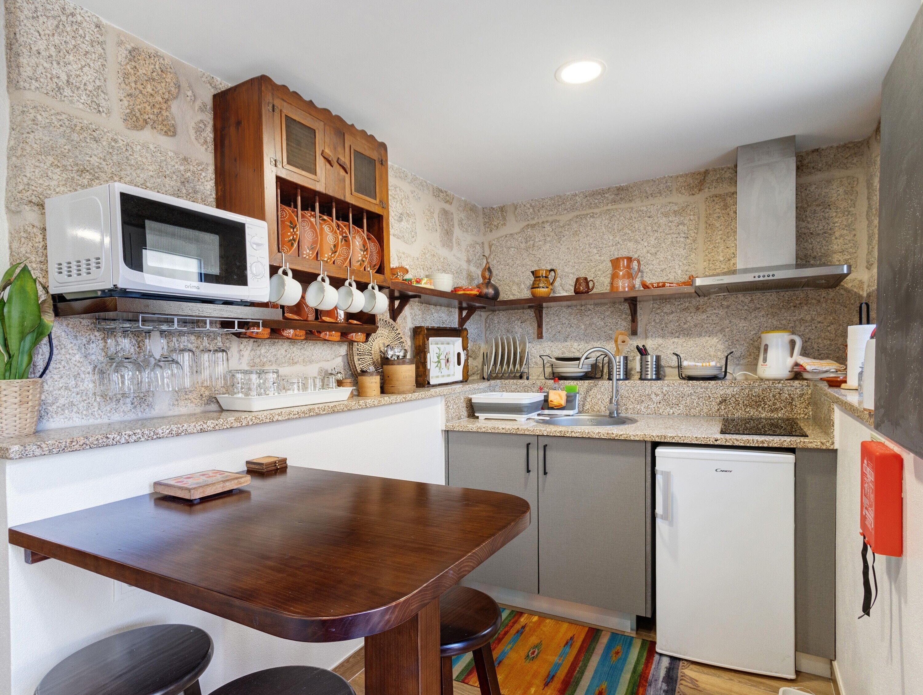 A compact kitchen with a microwave, wooden cabinets, a sink, and a dining area with a table and chairs.
