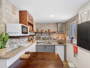A compact kitchen with a microwave, sink, and wooden cabinets.