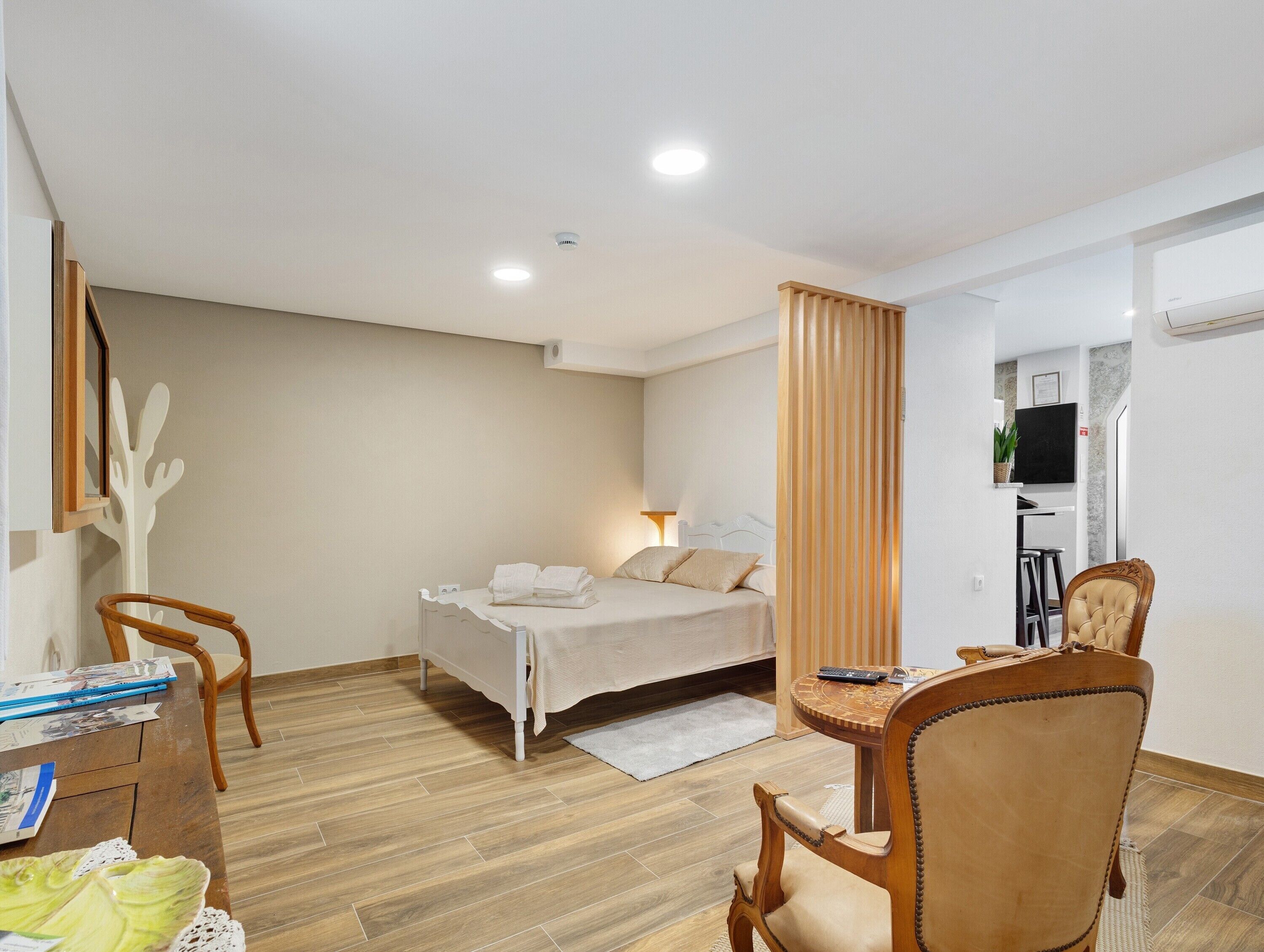 Une chambre d’hôtel avec un lit, un bureau et une chaise, une télévision et un plancher en bois.