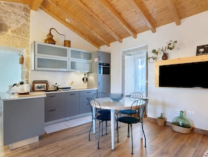A modern kitchen with grey cabinets, a wooden ceiling, and a dining area with a table and chairs.