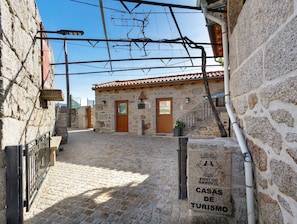 A stone building with a tiled roof, a wooden door, and a staircase leading to a second floor.