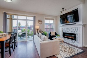 A modern living room with a fireplace, a television, and a dining area with a table and chairs.