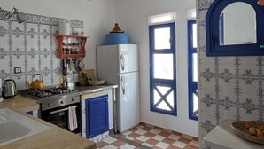 Une cuisine avec un carrelage à motifs, une cuisinière, un réfrigérateur et un évier.