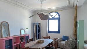 Un salon spacieux avec une table à manger en bois, un meuble de rangement rose et une grande fenêtre.