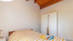 Un dormitorio con cama, mesita de noche, lámpara, armario y espejo.