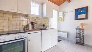 Cocina con alacenas blancas, estufa, ventana y radiador.