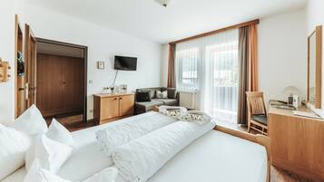 A hotel room with a bed, a desk, a chair, a television, and a wardrobe.