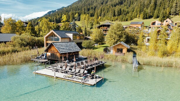 A lakeside wooden cabin with a dock, clear water, and surrounding forested hills. - Regitnig‑Lake‑Hideaway am Weissensee (Weissensee)