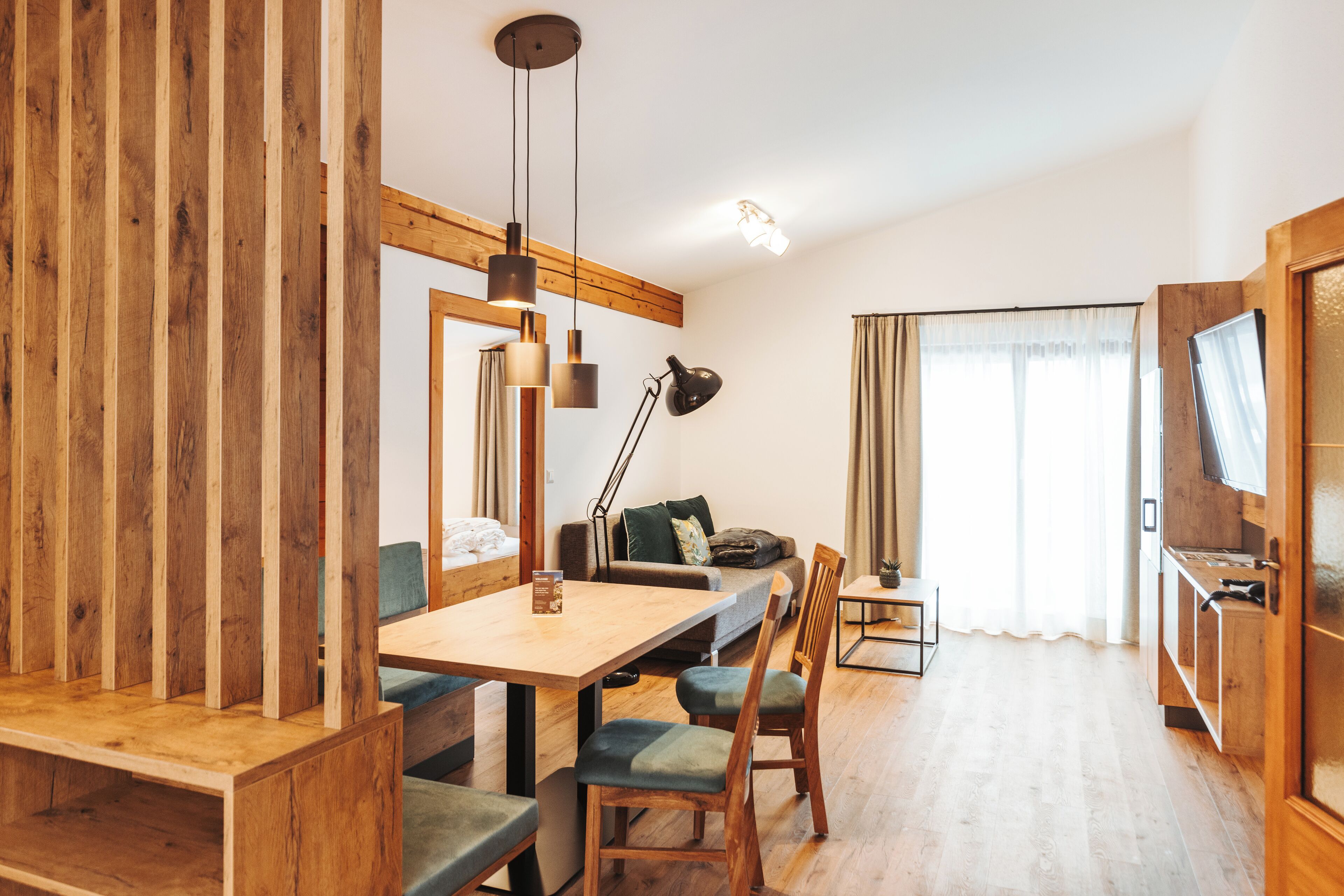 Una sala moderna con una mesa de comedor de madera, sillas, un sofá y un televisor.