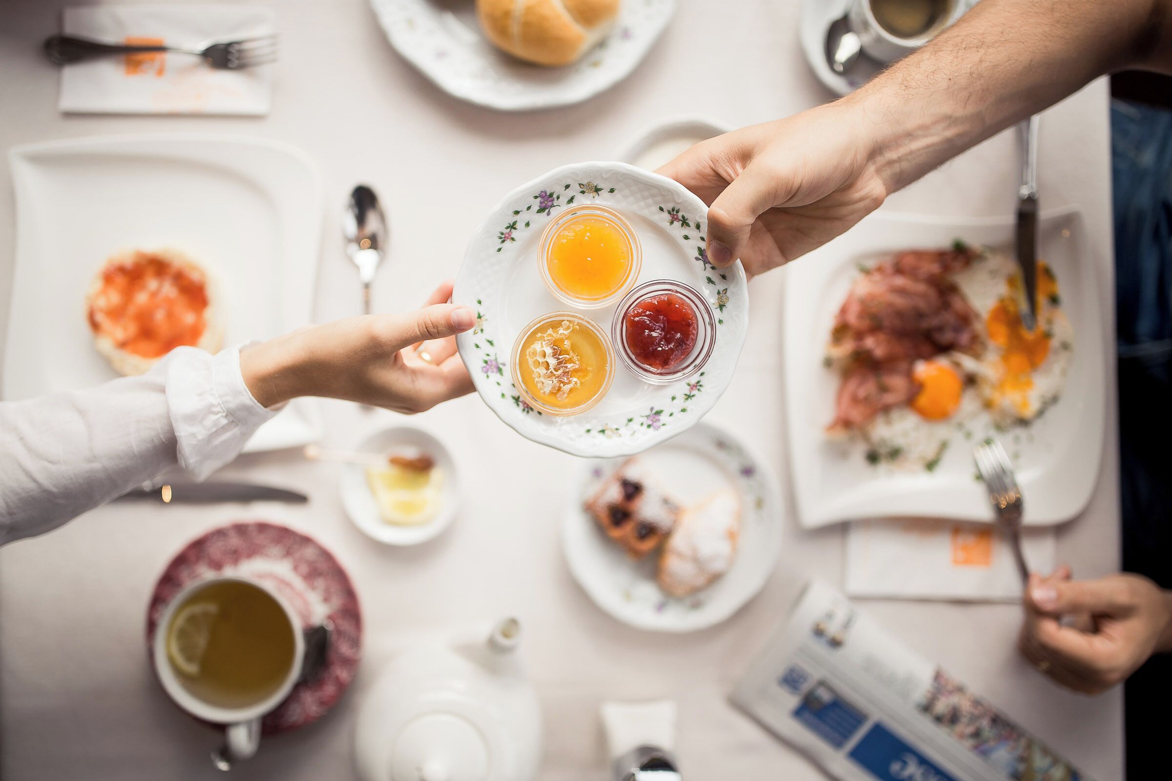 A dining table with plates of food, utensils, and a teapot.