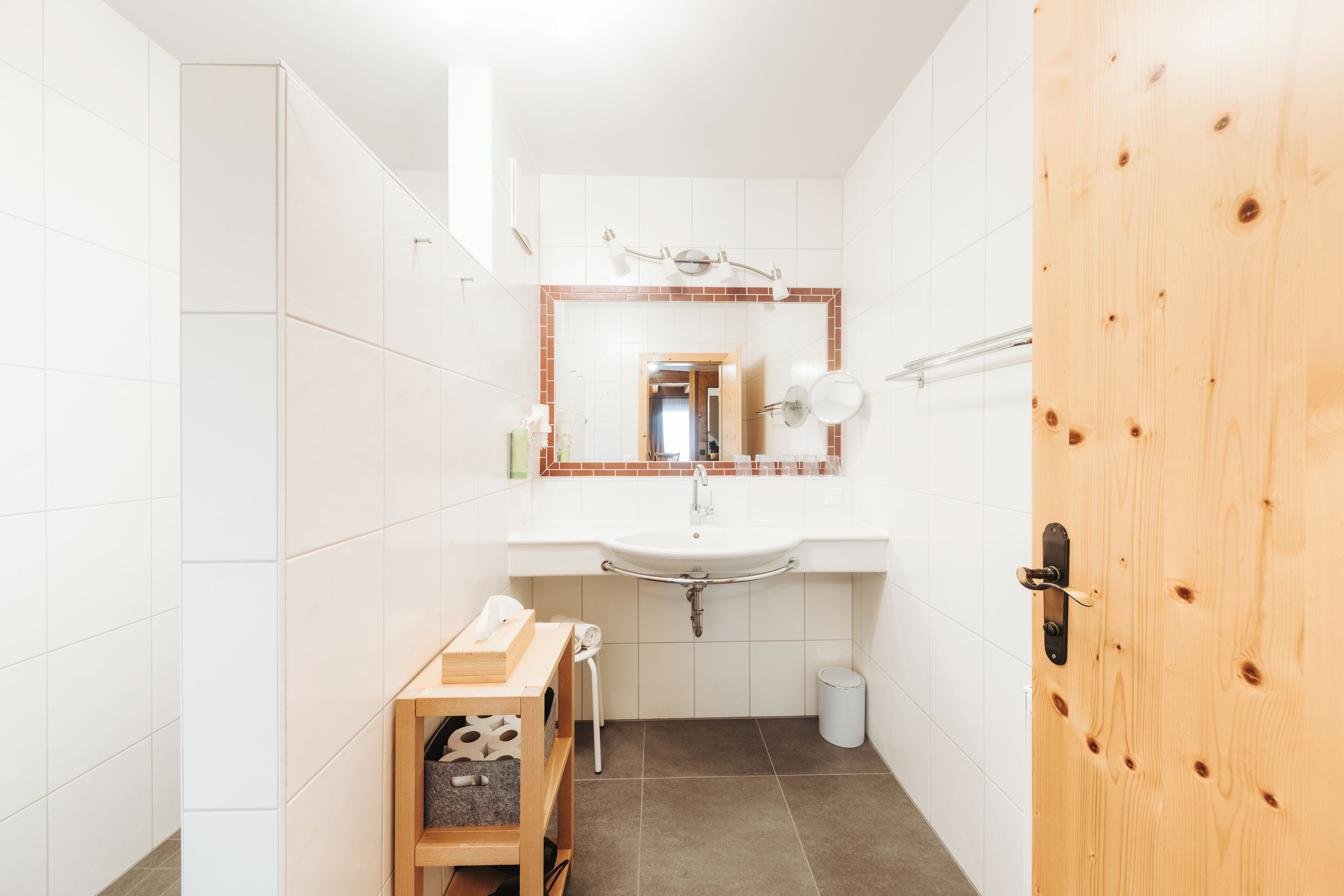 A bathroom with a white sink, a mirror, and a wooden door.