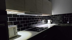 A modern kitchen with black and white tiles, a built-in oven, and a coffee maker. - Woodside House (Forres)