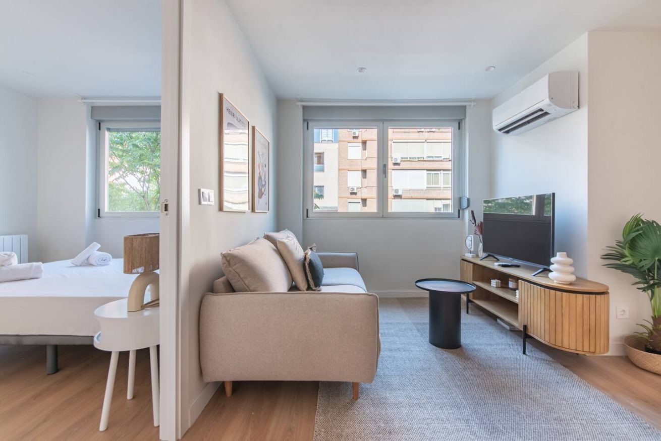 Un salon moderne comprenant un canapé, un téléviseur et un coin repas avec une table et des chaises.