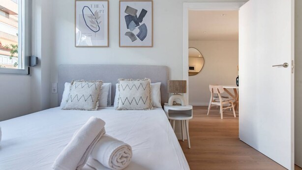 Ein Hotelzimmer mit einem Bett, einem Schreibtisch und einem Stuhl. Zwei gerahmte Bilder hängen an der Wand.