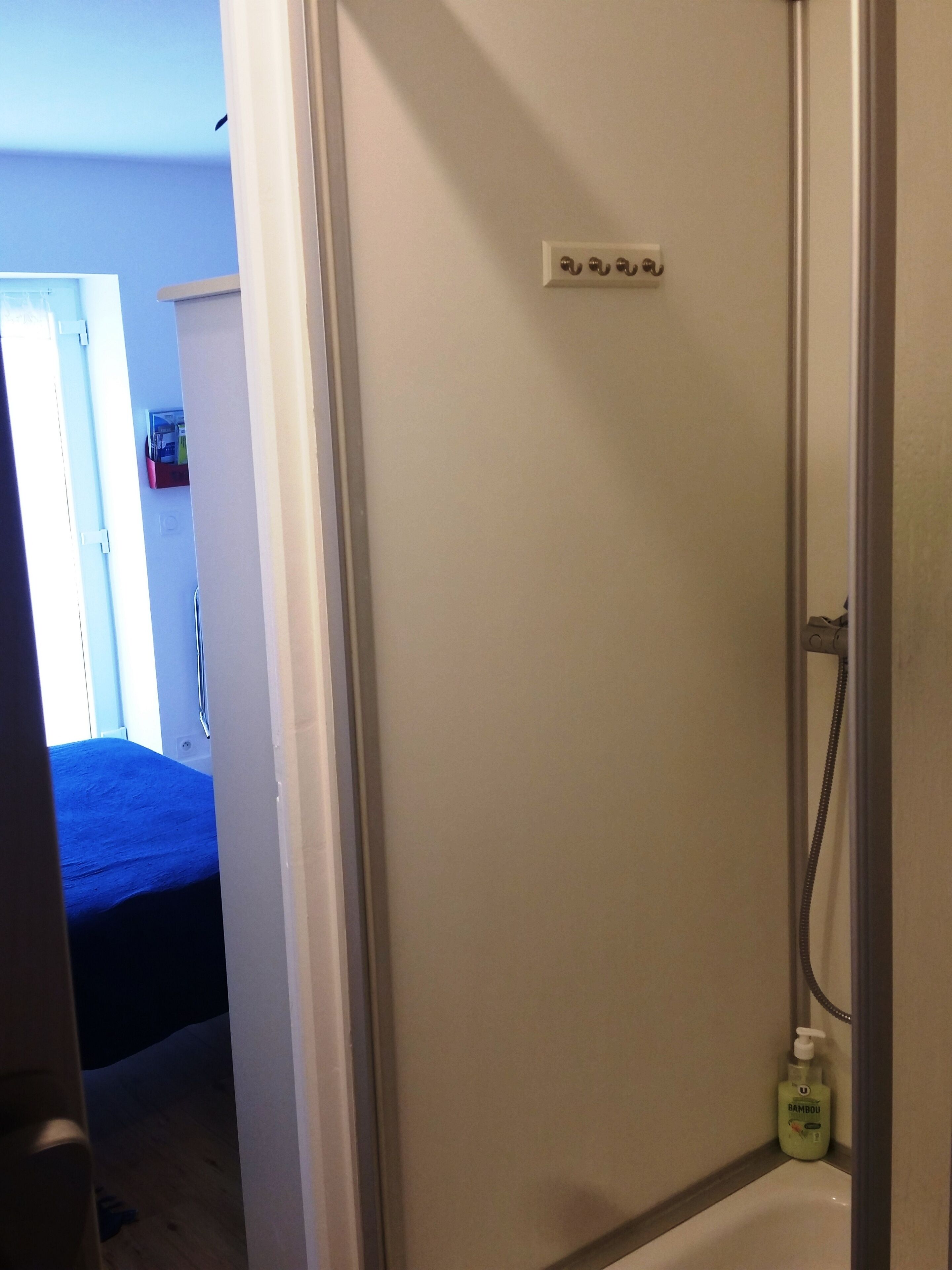 Une salle de bain avec une douche, des toilettes et un lavabo. Il y a une bouteille de shampoing sur le lavabo.