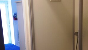 Ein Badezimmer mit Dusche, Toilette und Waschbecken. Auf dem Waschbecken steht eine Flasche Shampoo.