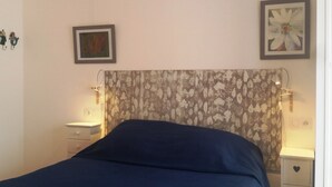 Ein Schlafzimmer mit einem Bett, einem Nachttisch, einer Lampe und zwei gerahmten Bildern an der Wand.