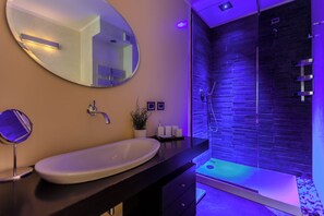 A modern bathroom with a large oval sink, a round mirror, and a glass-enclosed shower area. - Stylish Suite in Fashion District - Corso Venezia (Milano)