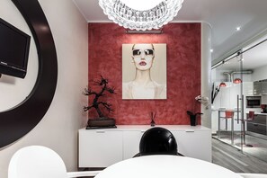 A modern interior with a red accent wall, a mounted TV, a decorative tree, and a minimalist dining area. - Stylish Suite in Fashion District - Corso Venezia (Milano)