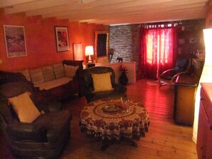A cozy living room with a sofa, armchairs, a coffee table, and a stone wall. - House 2 pers Volvic parc des Volcans, shady garden. Comfortable 70 m² . (Volvic)