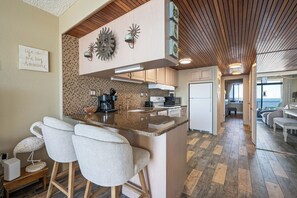 A modern kitchen with a central island, bar stools, and a decorative backsplash. - Spectacular Ocean Views from Lovely Condo with an Outdoor Pool (Ocean City)