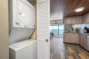 A laundry area with a washer and dryer, wooden cabinets, and a view of the ocean. - Spectacular Ocean Views from Lovely Condo with an Outdoor Pool (Ocean City)