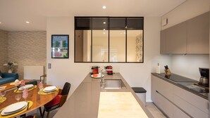 Una cocina moderna con una encimera larga, un fregadero y una zona de comedor con sillas y una mesa dispuesta para cuatro.