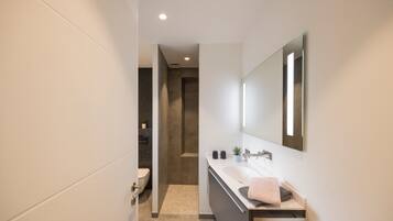 Un baño moderno con un lavamanos blanco, un espejo grande y un perchero para toallas.