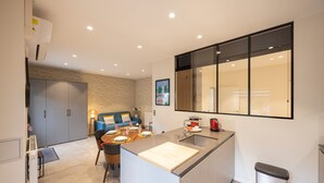 Una cocina moderna con una isla central, un área de comedor con sofá azul y un ventanal grande.