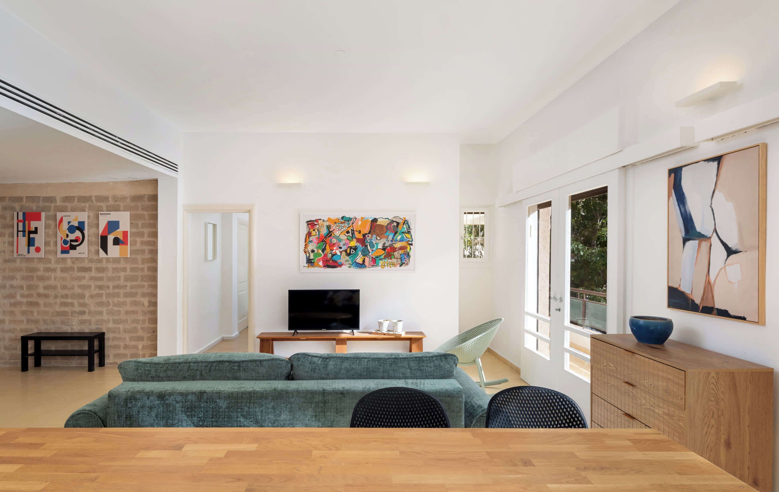 Ein modernes Wohnzimmer mit einer Couch, einem Fernseher und Kunstwerken an der Wand.