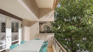 A balcony with a white table and turquoise chairs, overlooking a tree and parked cars. - Peaceful 2BR Apt w/ Balcony by HolyGuest (Tel Aviv-Yafo)