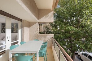 A balcony with a white table and turquoise chairs, overlooking a tree and parked cars. - Peaceful 2BR Apt w/ Balcony by HolyGuest (Tel Aviv-Yafo)