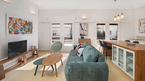 A modern living space with a TV, sofa, dining area, and kitchen. - Peaceful 2BR Apt w/ Balcony by HolyGuest (Tel Aviv-Yafo)