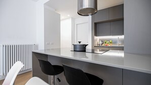 A modern kitchen with a central island, black bar stools, a built-in stove, and a stainless steel range hood. - Italianway Comfort - Vincenzo Monti 29 F (Milan)