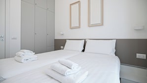 A hotel room with a bed, two pillows, a nightstand, a wall-mounted light, and a wardrobe. - Italianway Comfort - Vincenzo Monti 29 F (Milan)