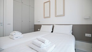 A hotel room with a bed, two pillows, a nightstand, a wall-mounted light, and a wardrobe. - Italianway Comfort - Vincenzo Monti 29 F (Milan)