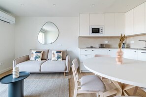 Eine moderne Küche mit weißen Schränken, einer Mikrowelle und einem Essbereich mit einem runden Tisch und Stühlen.