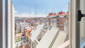 Vista sulla città da una finestra, con diversi edifici a tetti piatti e alcuni dotati di antenne.