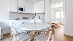 Una cucina moderna con mobili bianchi, un forno a microonde e un'area pranzo con un tavolo rotondo e sedie.