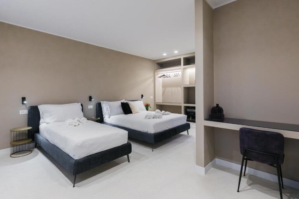Habitació d'hotel moderna amb dos llits, un escriptori i una cadira.