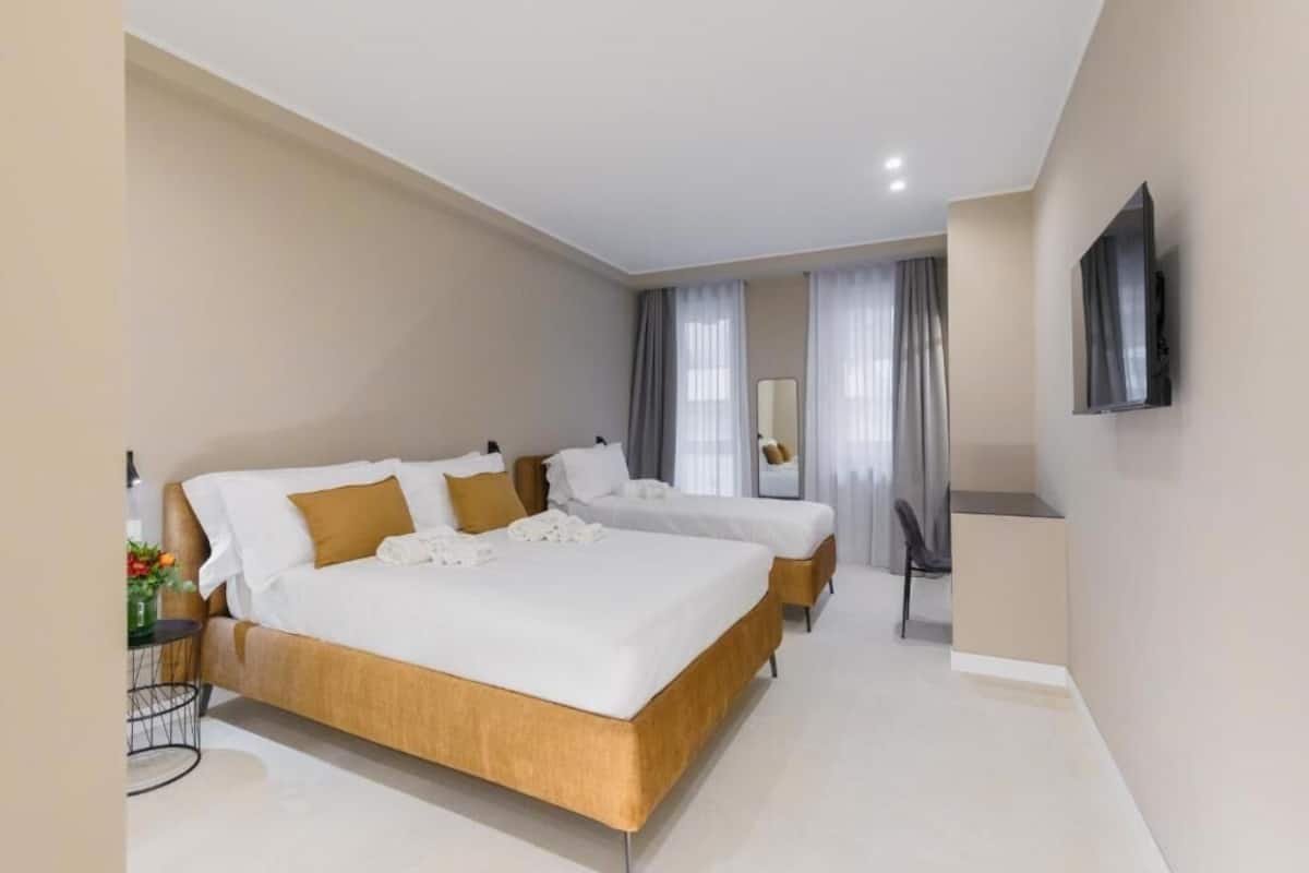 Une chambre d’hôtel avec un grand lit, un bureau et un téléviseur fixé au mur.