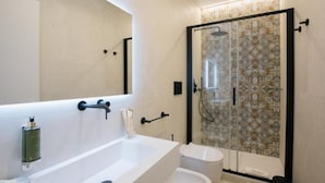 A modern bathroom with a large mirror, a white sink, a toilet, and a glass-enclosed shower area. - Il Pumo Apulian Rooms Bari Calefati 141 (Bari)