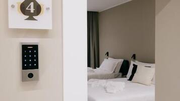 Una habitación de hotel con cama, panel de control en la pared y una puerta con un número.