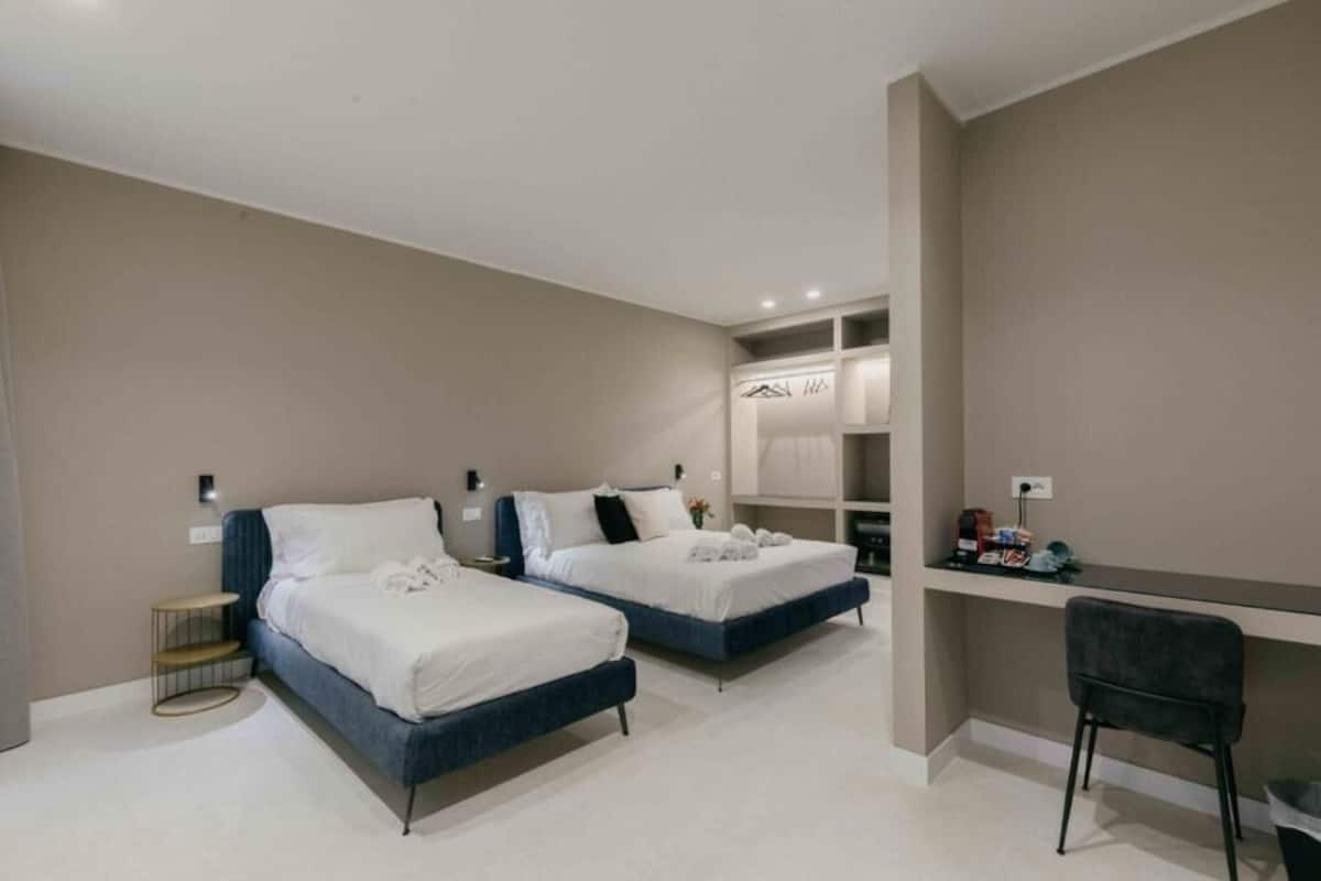Une chambre d’hôtel moderne avec deux lits, un bureau et une chaise.
