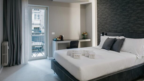 A modern hotel room with a large bed, a desk, and a view of the outside balcony. - Il Pumo Apulian Rooms Bari Calefati 141 (Bari)