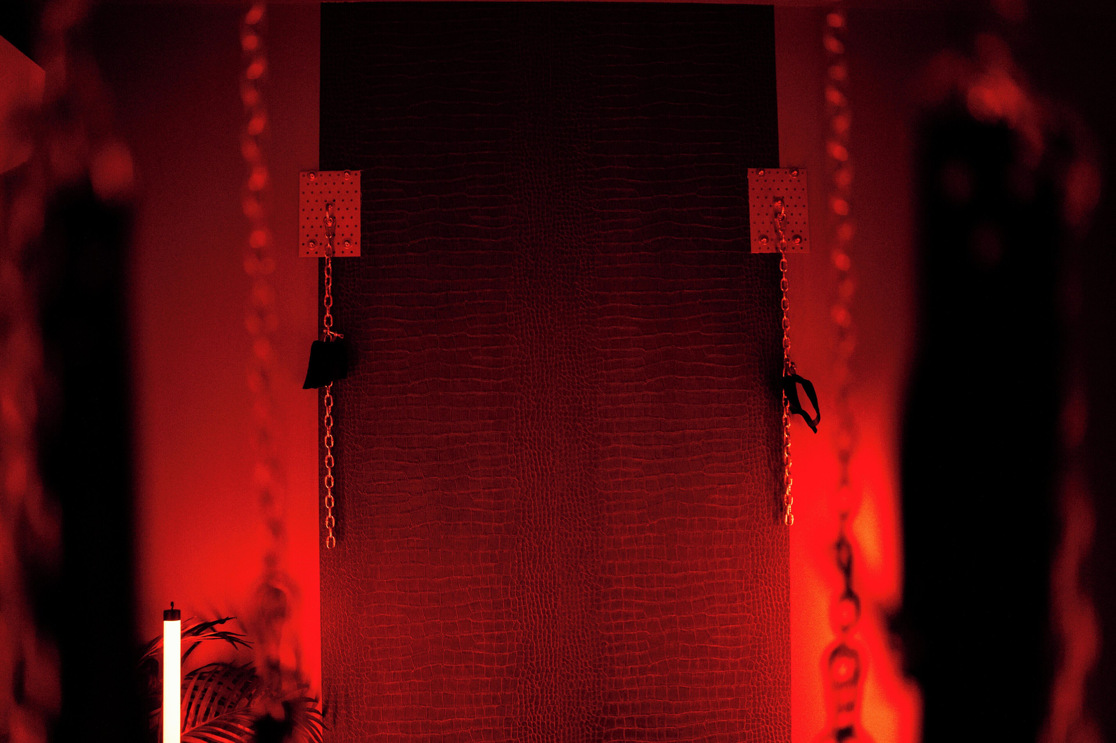 A red textured wall with two square light fixtures and chains hanging from the ceiling.