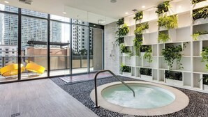 Ein moderner Innenpoolbereich mit Whirlpool, umgeben von Glaswänden und einer vertikalen Bepflanzung.