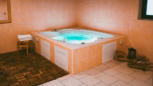 Ein Wellnessraum mit Whirlpool, einem Holzschemel und einem kleinen Tisch mit Handtüchern.