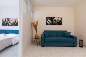 A modern room with a bed, a teal sofa, and two wall-mounted paintings.